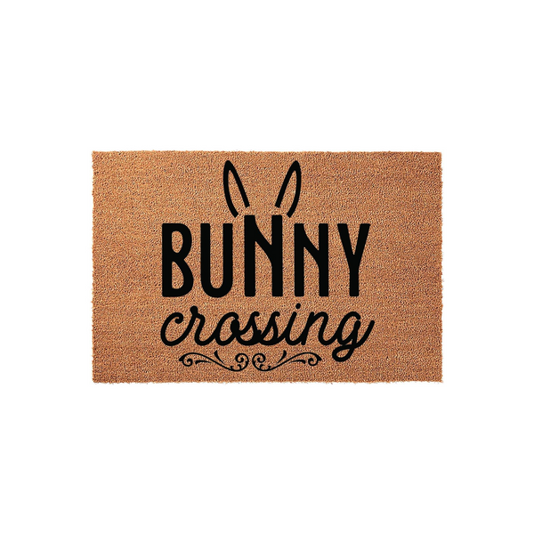 Bunny Crossing coir doormat featuring a natural tan fiber texture with black printed text and cute rabbit ears, making a festive spring or Easter front porch decor piece for your home entrance on a clean white background.