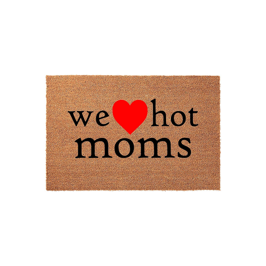 We Heart Hot Moms Doormat featuring a natural coir fiber texture with bold black text and a bright red heart icon centered on the mat, creating a humorous and trendy entryway decor piece for a modern home or apartment front door