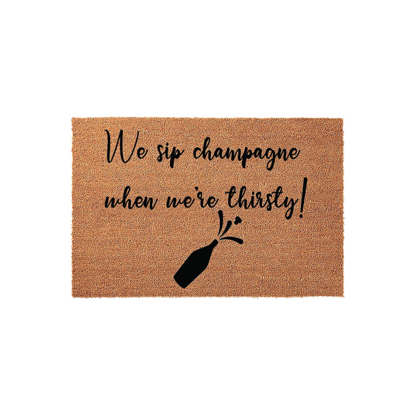 Funny Champagne Quote Coir Doormat featuring the text We sip champagne when we are thirsty in elegant black script, accompanied by a graphic of a popping champagne bottle on a natural brown textured coconut fiber background.