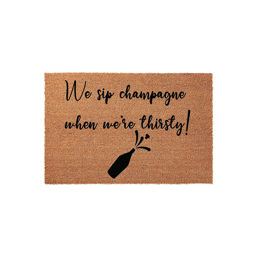 Funny Champagne Quote Coir Doormat featuring the text We sip champagne when we are thirsty in elegant black script, accompanied by a graphic of a popping champagne bottle on a natural brown textured coconut fiber background.