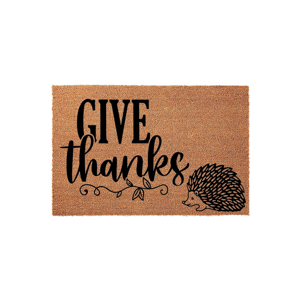 Give Thanks Hedgehog Coir Doormat featuring a natural brown fiber texture with black printed text and a cute hedgehog illustration, creating a festive autumn entryway decor piece for your front porch or home entrance during the