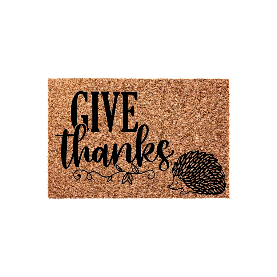 Give Thanks Hedgehog Coir Doormat featuring a natural brown fiber texture with black printed text and a cute hedgehog illustration, creating a festive autumn entryway decor piece for your front porch or home entrance during the