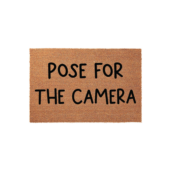 Pose for the Camera coir doormat featuring a natural tan fiber texture and bold black lettering, designed as a fun and welcoming front porch entrance mat for your home that encourages guests to smile as they arrive at your front