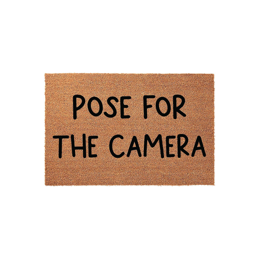 Pose for the Camera coir doormat featuring a natural tan fiber texture and bold black lettering, designed as a fun and welcoming front porch entrance mat for your home that encourages guests to smile as they arrive at your front