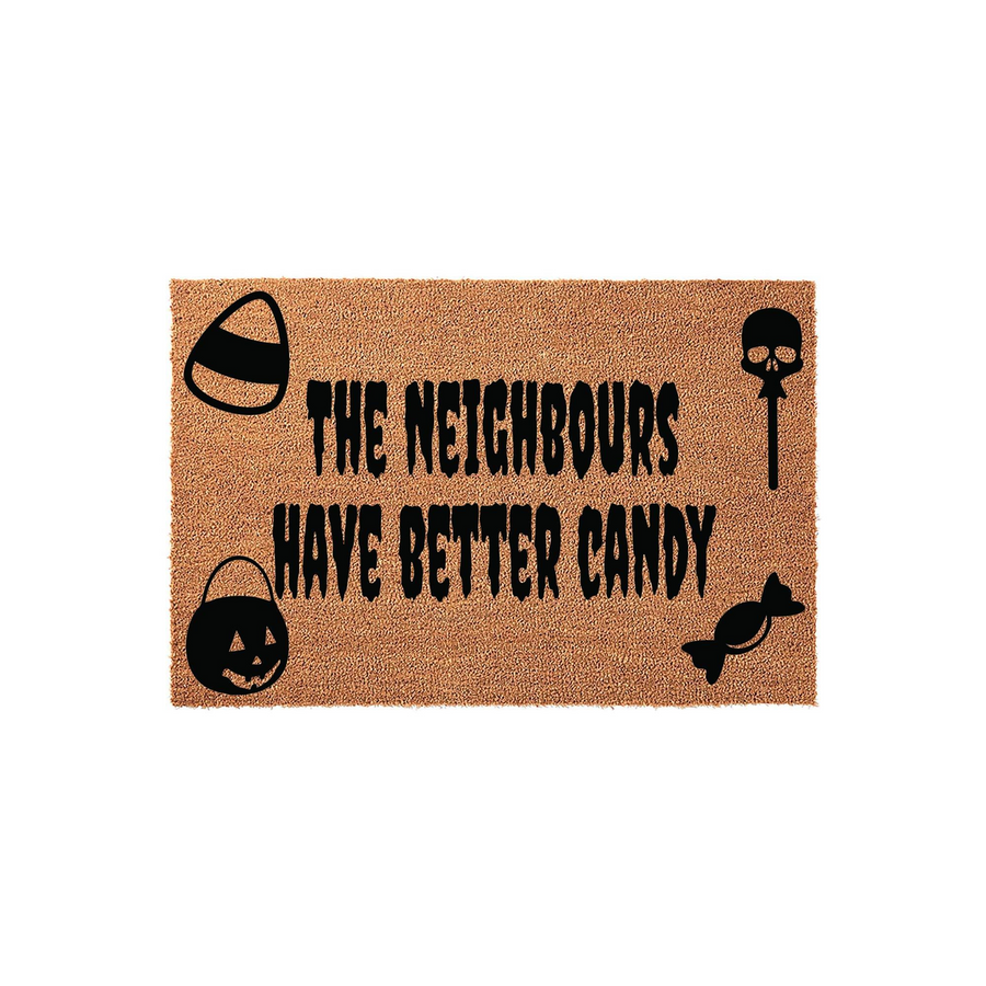 Funny Halloween doormat featuring the text The Neighbors Have Better Candy in a spooky font, surrounded by black icons of a candy corn, a skull lollipop, a jack-o-lantern bucket, and a piece of wrapped candy on a natural coir