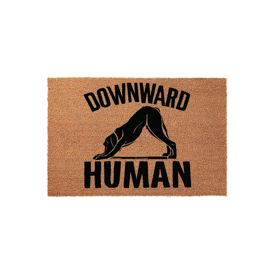 Downward Human yoga dog doormat featuring a natural coir texture with a black silhouette of a dog in a downward dog pose, humorously captioned with bold text on a plain white background for a fun entryway decor piece for pet