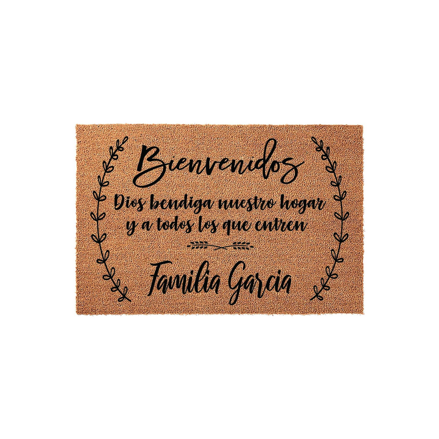 Personalized Spanish welcome doormat featuring natural coir fibers, printed with the phrase Bienvenidos Dios bendiga nuestro hogar y a todos los que entren, framed by elegant black leaf flourishes and a customizable family name.