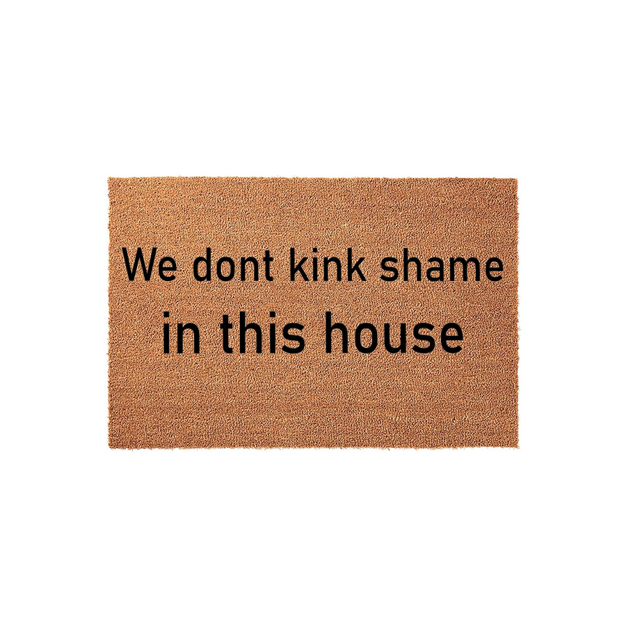 Funny We Dont Kink Shame In This House doormat featuring bold black text printed on a natural brown coir fiber mat, providing a humorous and welcoming entrance decor piece for your front porch or entryway on a clean white