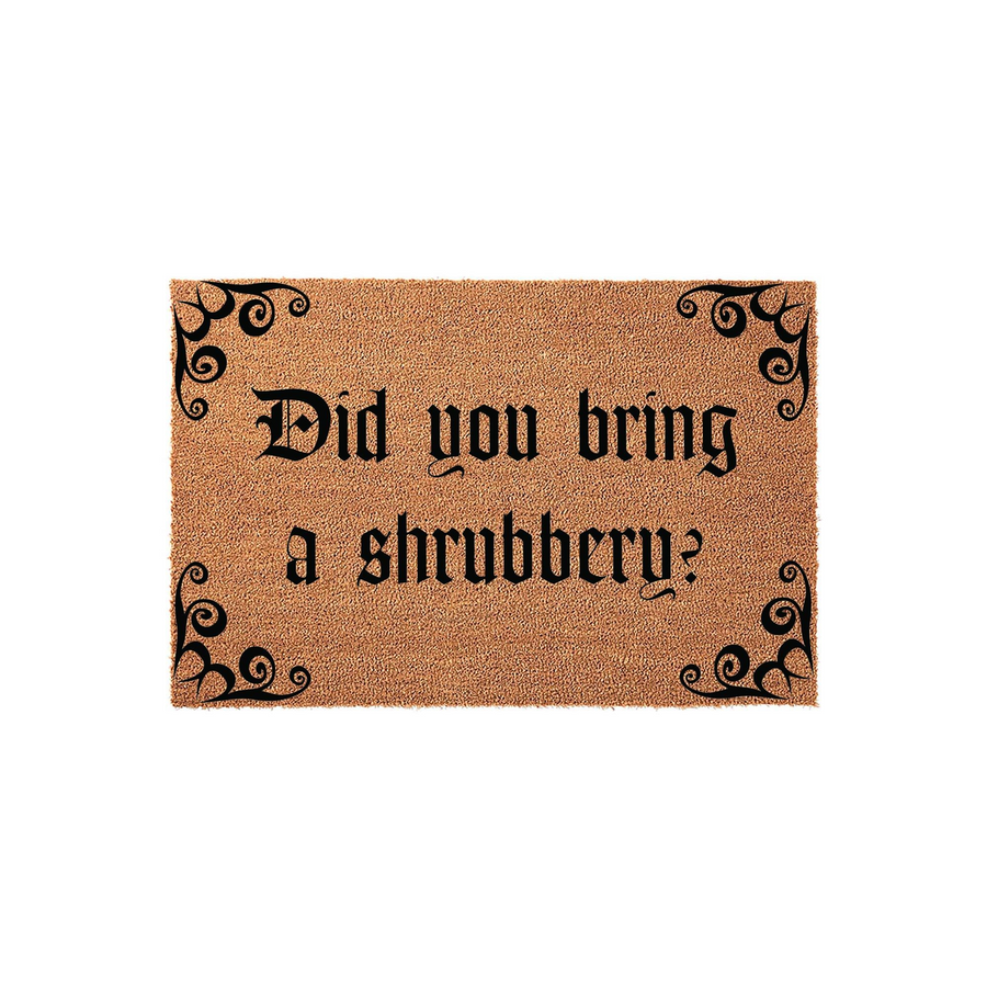 Funny movie quote doormat featuring the text Did you bring a shrubbery in a bold gothic font, set against a natural brown coir fiber background with decorative black scrollwork accents in each of the four corners of the