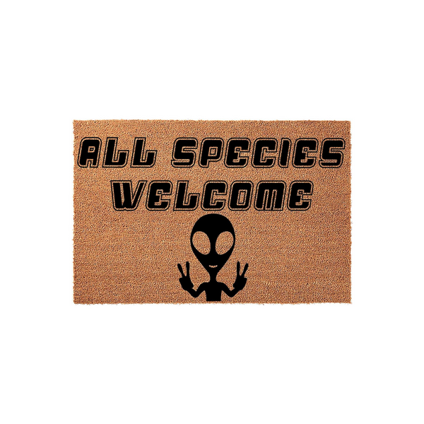 All Species Welcome alien doormat featuring a natural coir texture with bold black text and a graphic of an extraterrestrial character making a peace sign, creating a fun and quirky entryway decor piece for any sci-fi fan home.