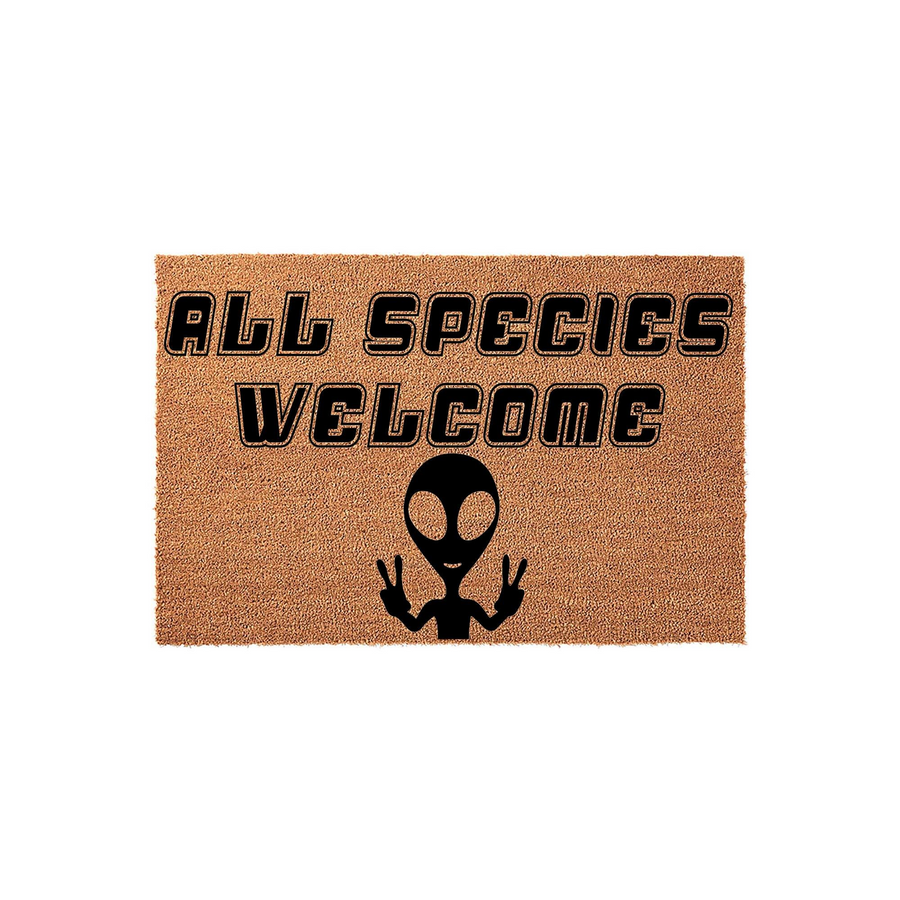 All Species Welcome alien doormat featuring a natural coir texture with bold black text and a graphic of an extraterrestrial character making a peace sign, creating a fun and quirky entryway decor piece for any sci-fi fan home.
