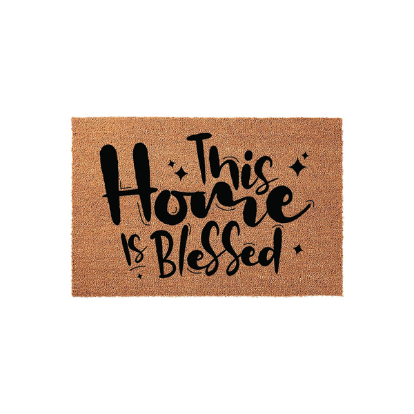 This Home Is Blessed coir doormat features a natural brown fiber texture with bold black script lettering that reads This Home Is Blessed, creating a welcoming and rustic entryway decor piece for your front porch or house