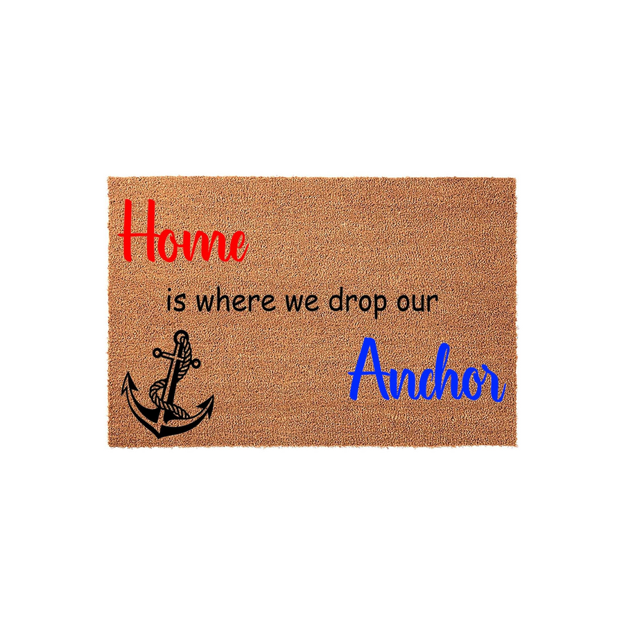 Nautical Home Is Where We Drop Our Anchor doormat made of natural coir fiber, featuring a black rope-wrapped anchor graphic and colorful text on a plain white background for a coastal or beach house entryway decor style.