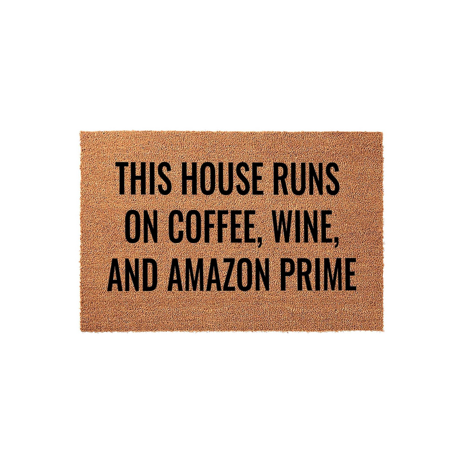 Funny Coffee and Wine Doormat featuring the text This House Runs On Coffee, Wine, And Amazon Prime in bold black lettering on a natural tan coir fiber background, perfect for a humorous front porch welcome mat for any modern home.