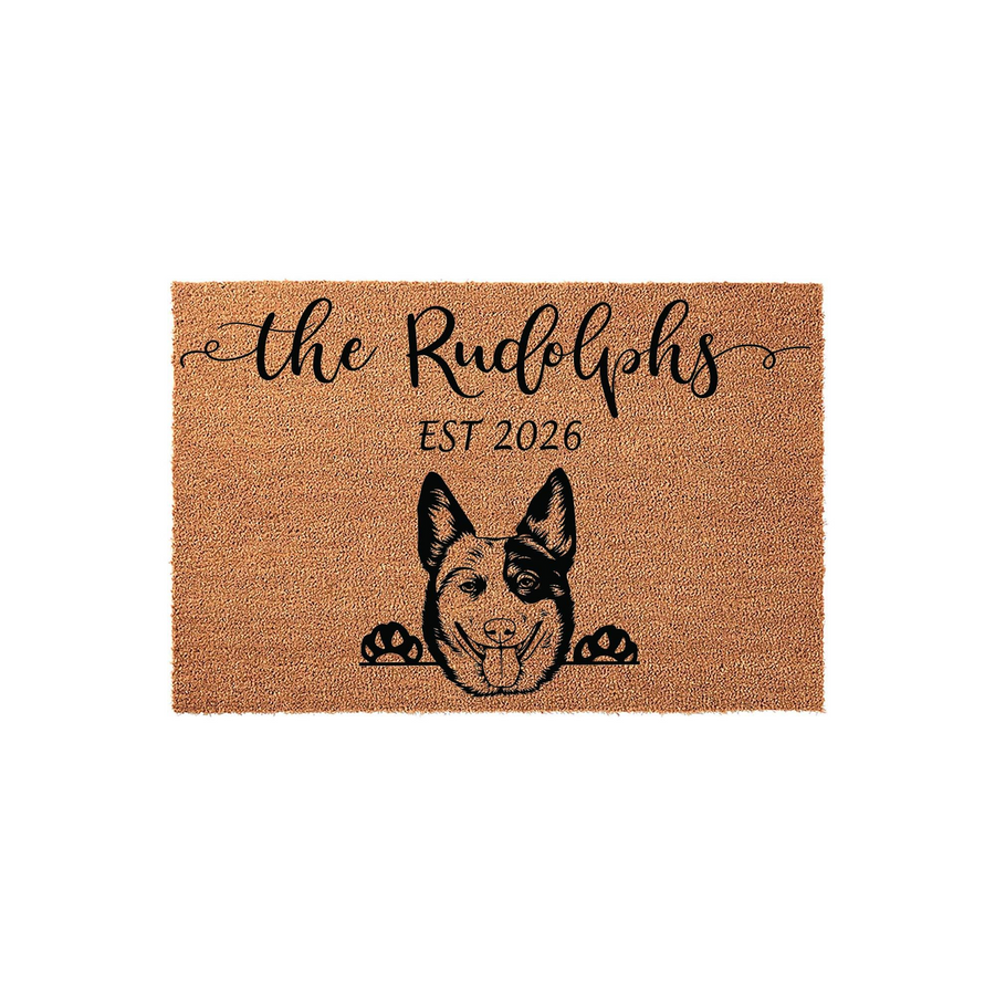 Personalized Blue Heeler dog doormat featuring a natural coir texture, custom family name text in elegant script, and a detailed illustration of a Cattle Dog peeking over the bottom edge for a charming entryway decor accent.