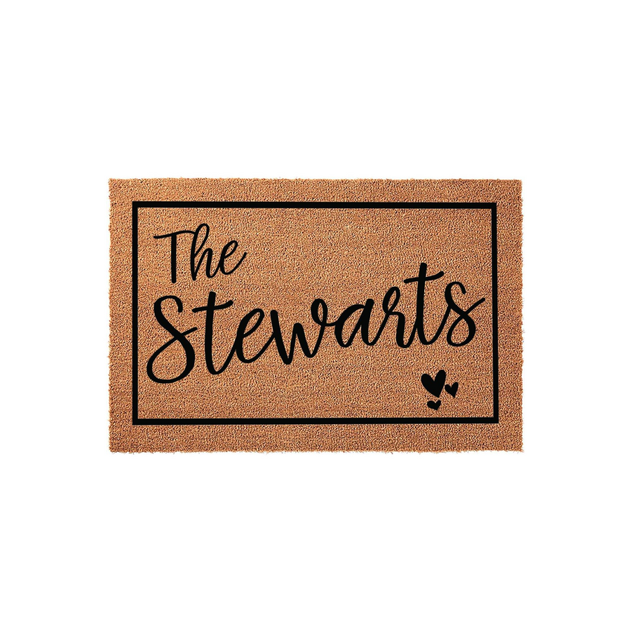 Personalized family name coir doormat featuring a black rectangular border, elegant script lettering for the family name, and three small decorative hearts in the corner, set against a clean white studio background for a modern