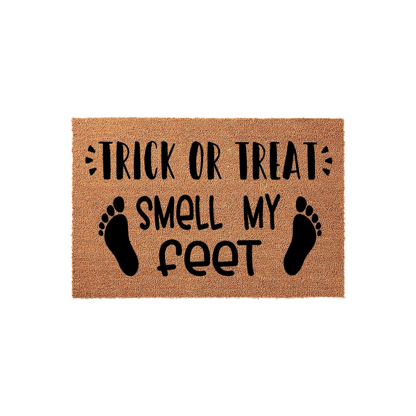 Trick or Treat Smell My Feet Halloween Doormat featuring a natural coir texture with bold black text and two footprint icons, creating a fun and festive entryway decoration for the spooky fall season on a plain white background.