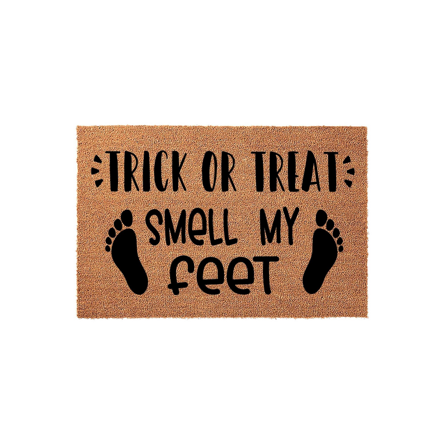 Trick or Treat Smell My Feet Halloween Doormat featuring a natural coir texture with bold black text and two footprint icons, creating a fun and festive entryway decoration for the spooky fall season on a plain white background.
