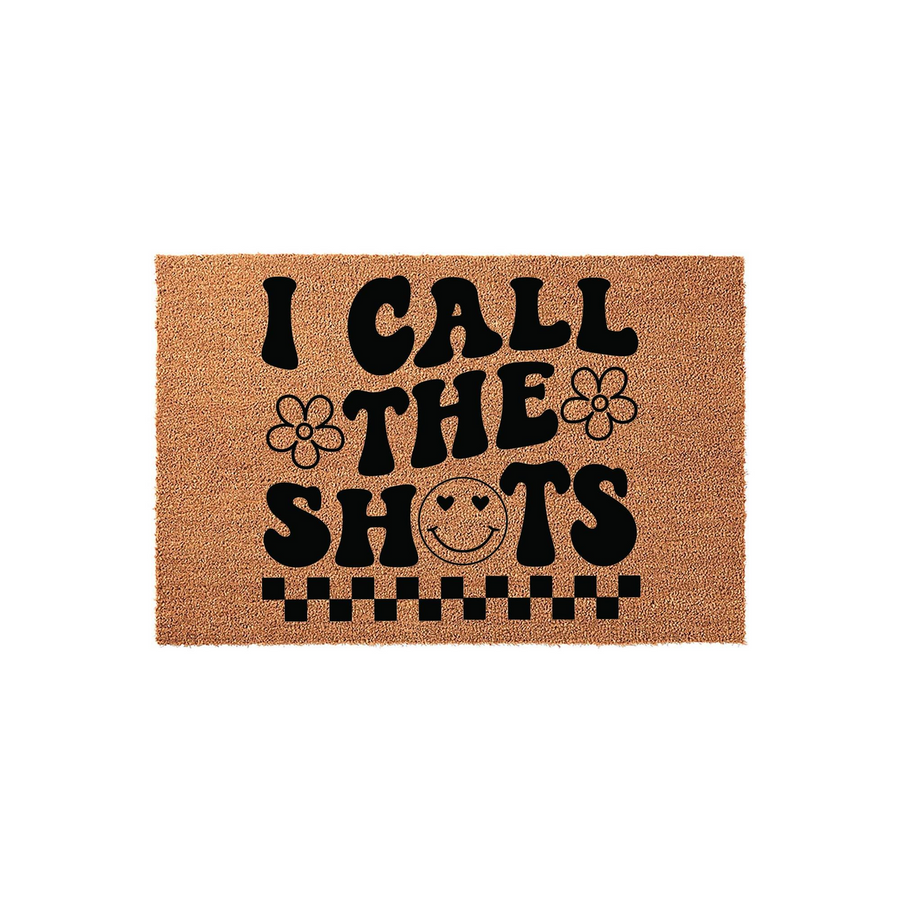 I Call The Shots coir doormat featuring a retro groovy design with black text, daisy flowers, a smiley face, and a checkered border on a natural brown fiber background, perfect for a fun and welcoming front porch entryway decor.