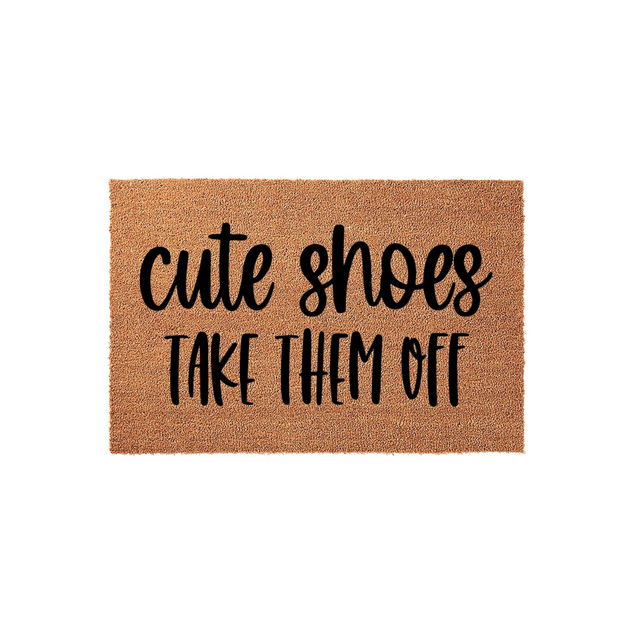 Cute Shoes Take Them Off funny doormat featuring bold black typography on a natural tan coir fiber background, designed to keep your entryway clean while adding a playful touch to your home decor for guests arriving at your front