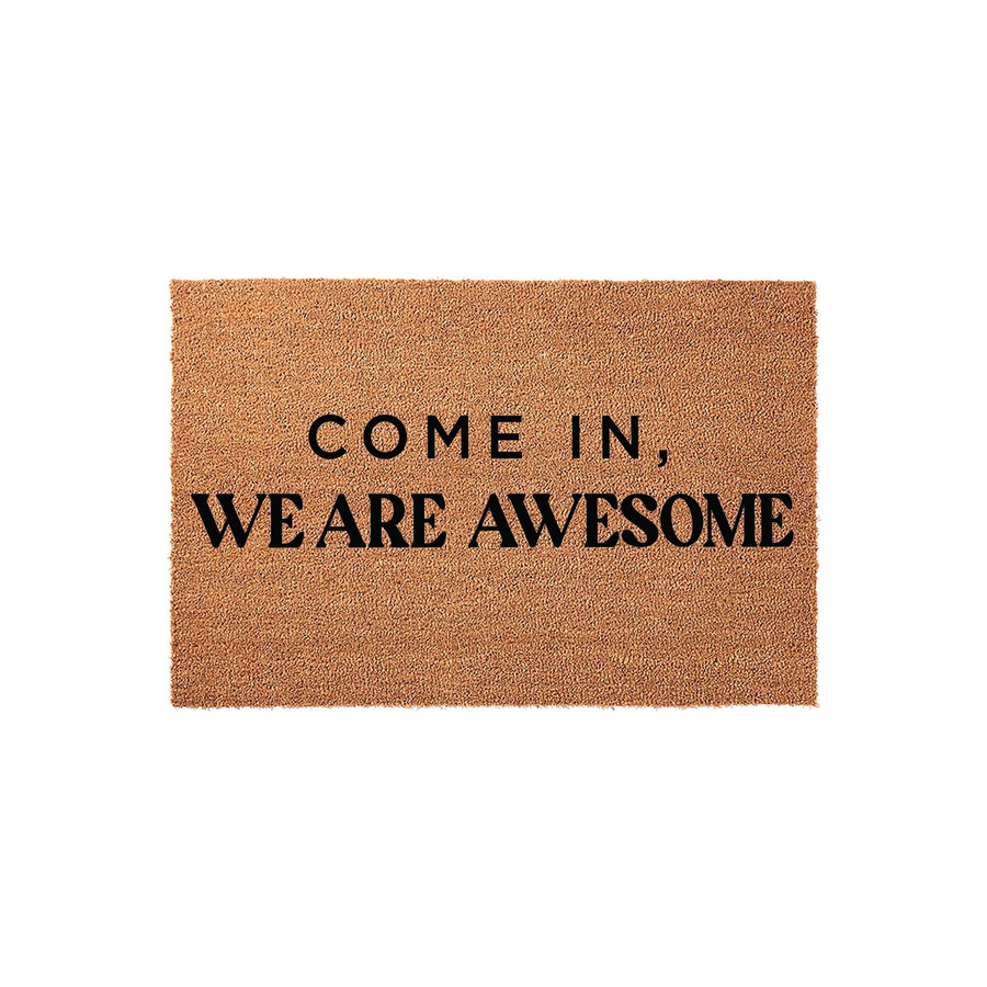Funny Come In We Are Awesome coir doormat featuring bold black text printed on a natural brown coconut fiber mat, providing a humorous and welcoming touch to any front porch entryway or home decor setting for guests to enjoy.