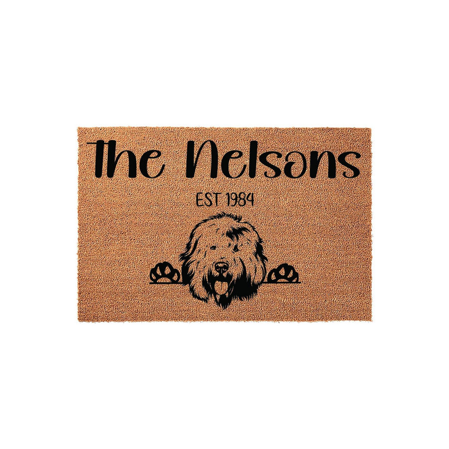 Personalized Doodle Dog Doormat featuring a cute shaggy dog peeking over the bottom edge, printed on a natural coir fiber mat with a custom family name and established year in bold black lettering for a welcoming front porch