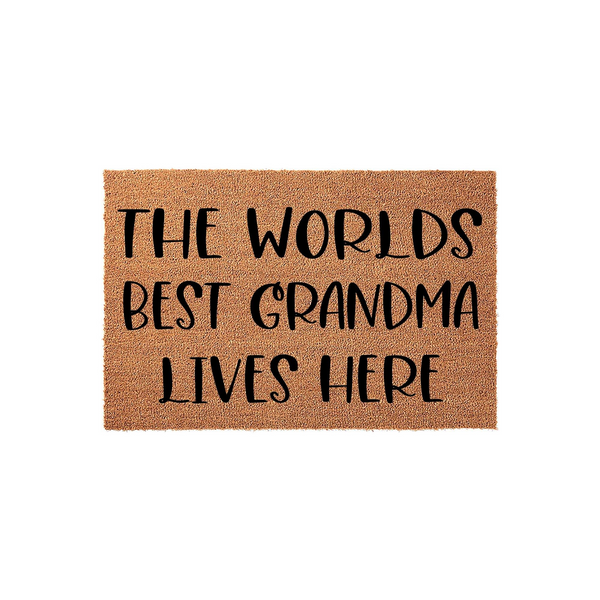 Worlds Best Grandma Lives Here coir doormat featuring bold black text printed on a natural brown coconut fiber mat, providing a welcoming and durable entryway floor covering for a grandmother's home on a clean white background.