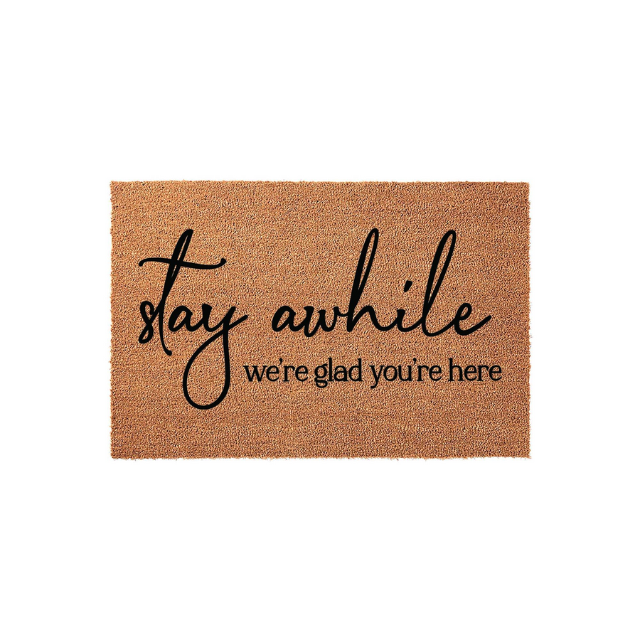 Stay Awhile We Are Glad You Are Here Coir Doormat featuring a natural tan fiber texture with black script and serif lettering, creating a welcoming front porch entrance for guests arriving at your home on a clean white background.