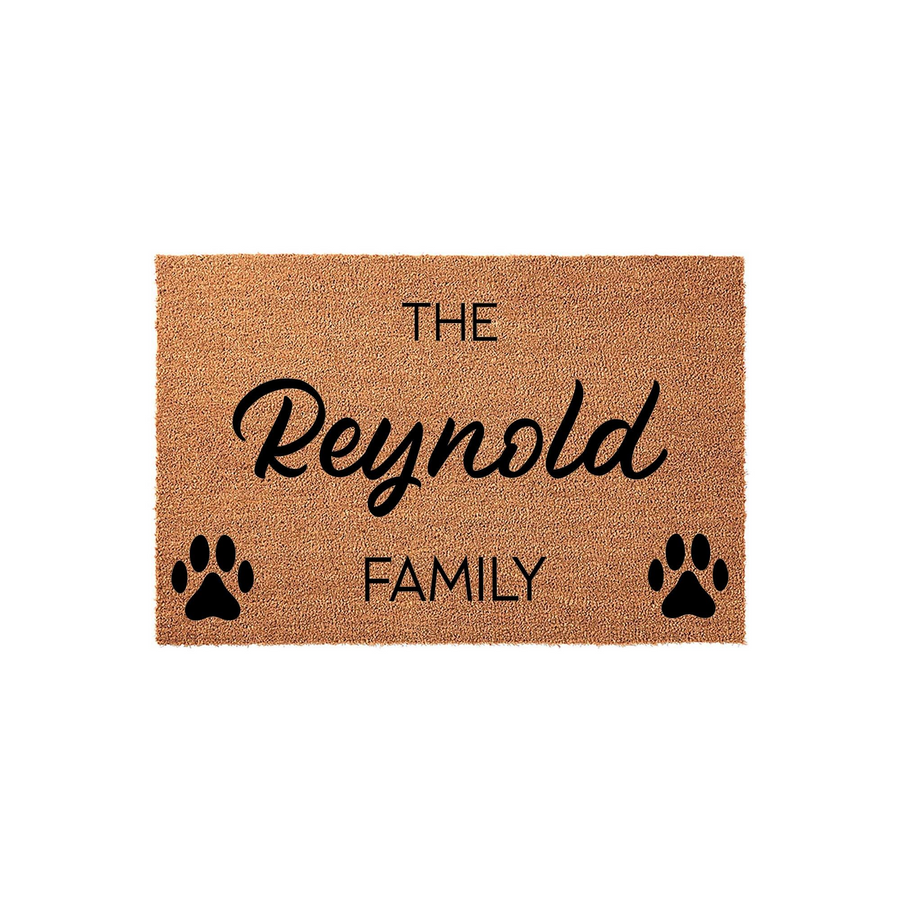 Personalized family name coir doormat featuring a natural brown fiber texture, printed with the text The Family and black paw prints on either side, creating a welcoming entryway decor piece for pet lovers and their homes.