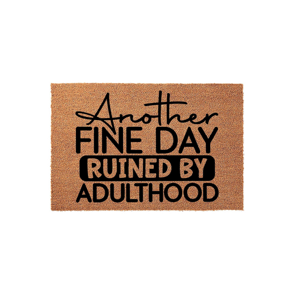 Funny Another Fine Day Ruined By Adulthood doormat featuring bold black typography printed on a natural tan coir fiber mat, creating a humorous and relatable welcome entrance piece for any home or apartment front porch entryway.