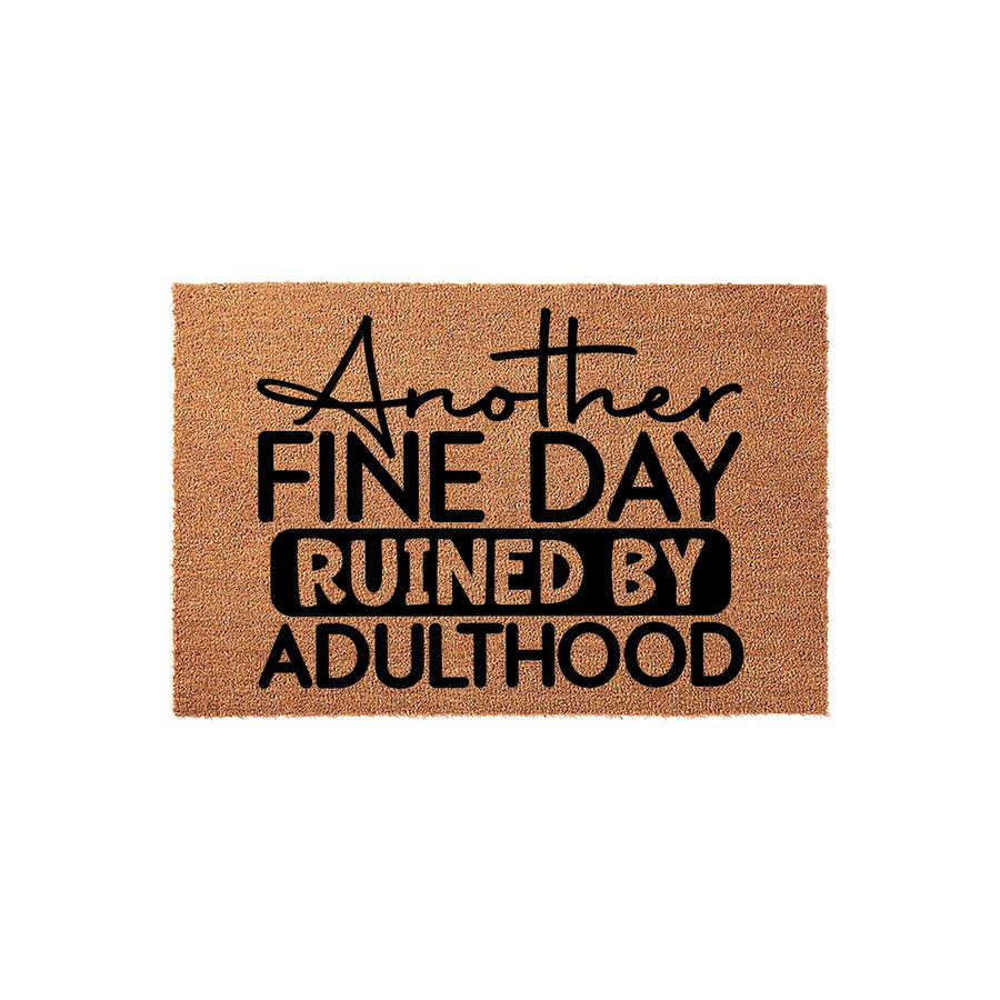 Funny Another Fine Day Ruined By Adulthood doormat featuring bold black typography printed on a natural tan coir fiber mat, creating a humorous and relatable welcome entrance piece for any home or apartment front porch entryway.