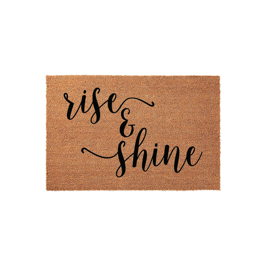 Rise and Shine coir doormat featuring elegant black cursive lettering centered on a natural brown coconut fiber mat, providing a welcoming and cheerful aesthetic for your front porch or entryway decor on a clean white background.