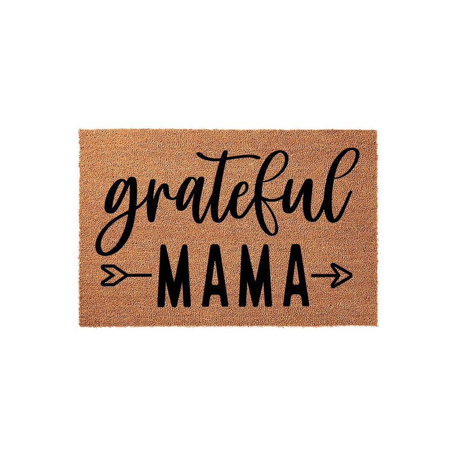 Grateful Mama coir doormat featuring a natural brown fiber texture with black text that reads grateful MAMA, accented by two simple arrow icons on either side of the word MAMA against a clean, plain white studio background.
