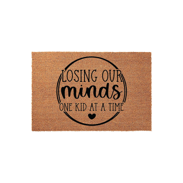 Funny Losing Our Minds One Kid At A Time coir doormat featuring black text inside a circular border on a natural tan fiber background, making a humorous welcome mat for parents or grandparents who enjoy a good laugh at home.