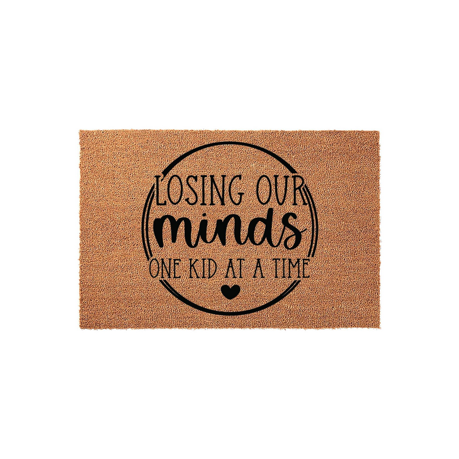 Funny Losing Our Minds One Kid At A Time coir doormat featuring black text inside a circular border on a natural tan fiber background, making a humorous welcome mat for parents or grandparents who enjoy a good laugh at home.