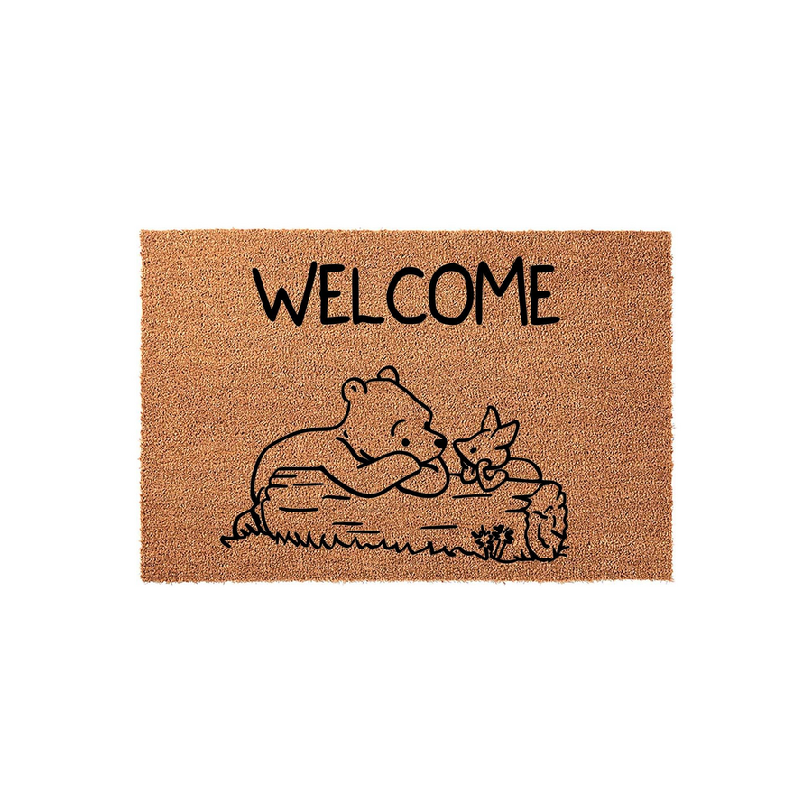 Winnie the Pooh and Piglet welcome doormat made of natural coir fiber, featuring a charming black line art illustration of the two friends resting on a log with the word Welcome printed in a simple, clean font above the