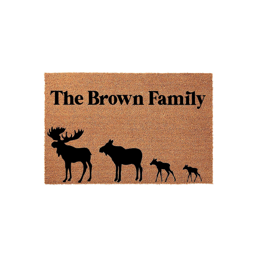 Personalized Moose Family Doormat featuring a natural coir texture with a black silhouette of a moose family and custom family name text printed in a bold, clean font against the rustic brown background of the outdoor entrance