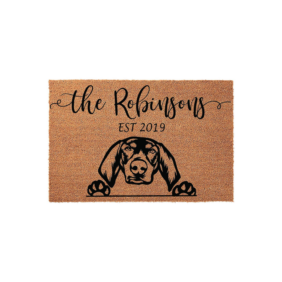 Personalized Dog Breed Coir Doormat featuring a custom family name and established year, showcasing a detailed black silhouette of a hound dog peeking over the edge with its paws resting on the natural brown textured fiber