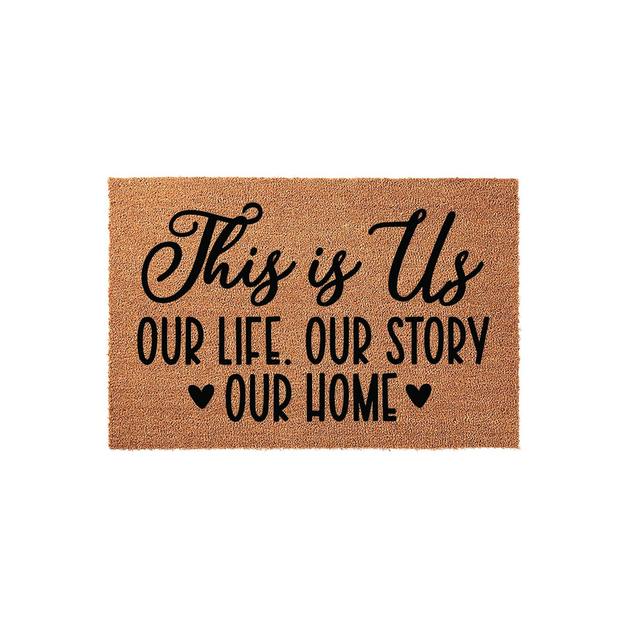 This is Us coir doormat featuring a natural brown fiber texture and bold black lettering that reads This is Us, Our Life, Our Story, Our Home, accented with two small hearts to create a welcoming entrance for any family front