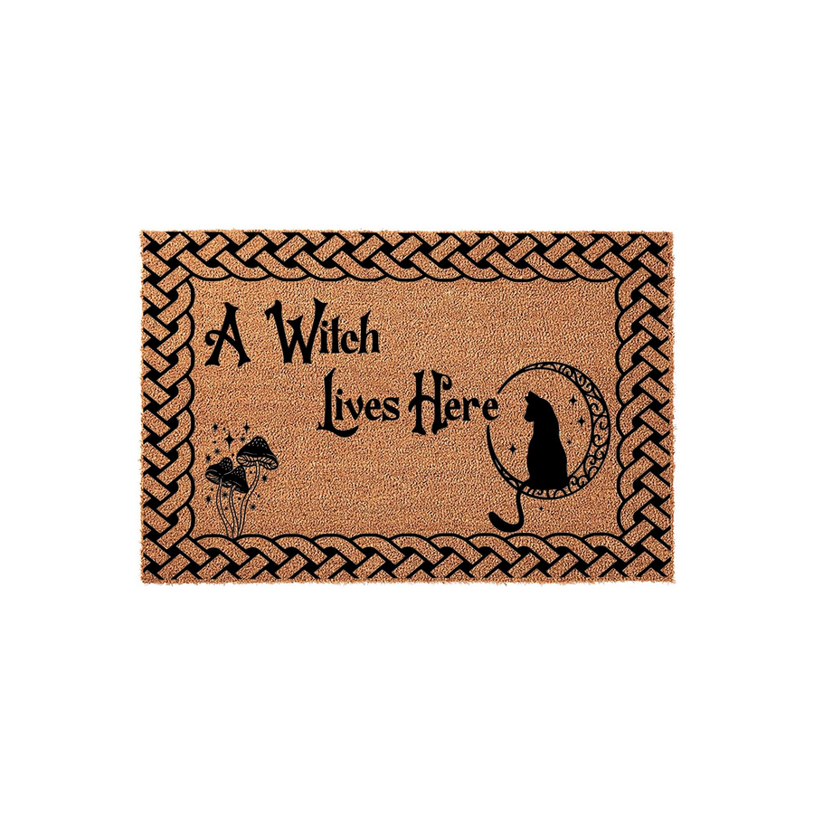 A Witch Lives Here coir doormat featuring a black cat sitting on a crescent moon, decorative mushrooms, and a braided border design on a natural tan fiber background, perfect for adding a spooky touch to your front porch entryway