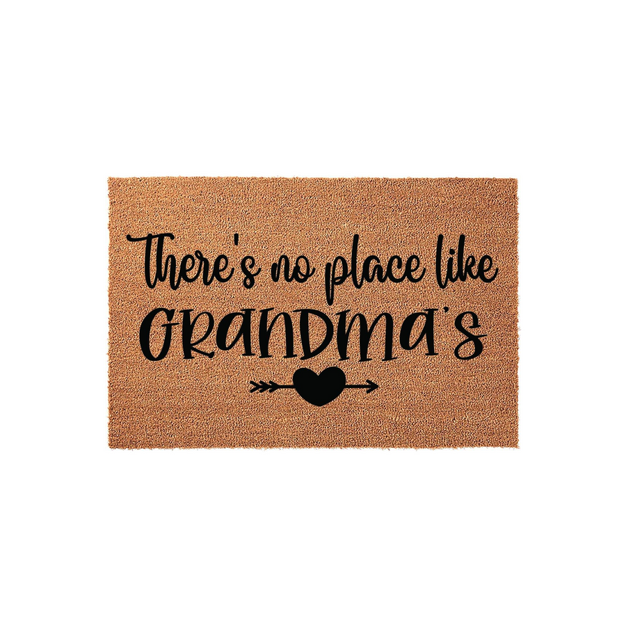 Grandma coir doormat featuring the text There is no place like Grandma's in black script lettering, accented by a small heart and arrow icon on a natural brown fiber background for a welcoming front porch entryway decor piece.