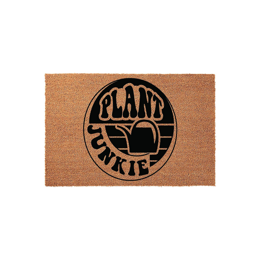 Plant Junkie coir doormat featuring a circular black graphic with a watering can icon and bold retro typography, set against a plain white background to highlight the natural tan texture of the durable outdoor welcome mat