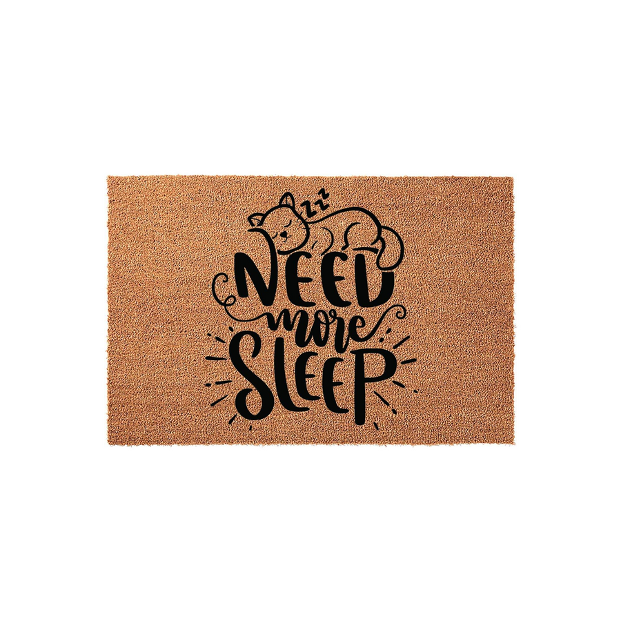 Need More Sleep cat doormat featuring a cute sleeping kitten illustration with zzz symbols, printed in bold black lettering on a natural brown coir fiber mat, perfect for a cozy entryway or a funny home decor accent for cat