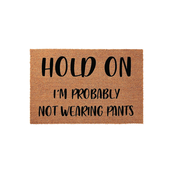 Funny Hold On I'm Probably Not Wearing Pants coir doormat featuring bold black text printed on a natural brown fiber mat, providing a humorous and welcoming touch to your front porch entryway decor against a clean white