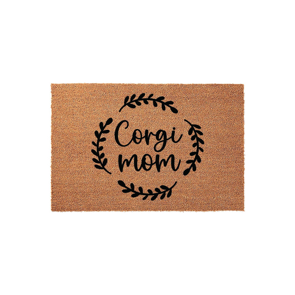 Corgi Mom natural coir doormat featuring a black printed design of the words Corgi mom surrounded by a delicate leafy wreath, set against a plain white background to highlight the textured brown fiber material of the welcome mat.