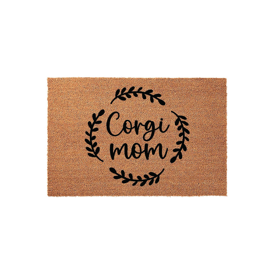 Corgi Mom natural coir doormat featuring a black printed design of the words Corgi mom surrounded by a delicate leafy wreath, set against a plain white background to highlight the textured brown fiber material of the welcome mat.