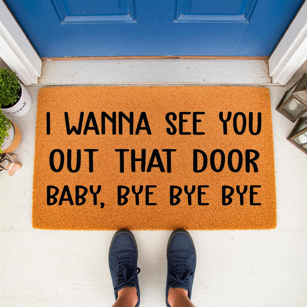 Funny Lyric Doormat featuring the text I Wanna See You Out That Door Baby, Bye Bye Bye in bold black lettering on a natural coir mat, placed on a white porch in front of a blue door with a person wearing blue sneakers standing on