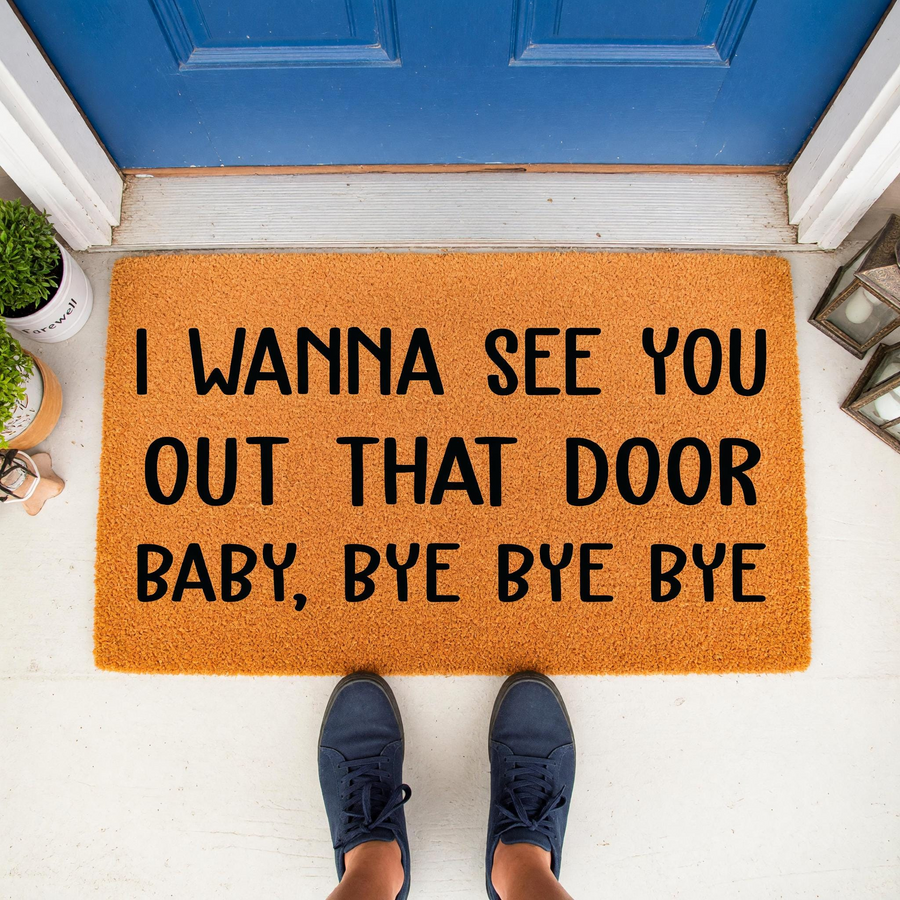 Funny Lyric Doormat featuring the text I Wanna See You Out That Door Baby, Bye Bye Bye in bold black lettering on a natural coir mat, placed on a white porch in front of a blue door with a person wearing blue sneakers standing on
