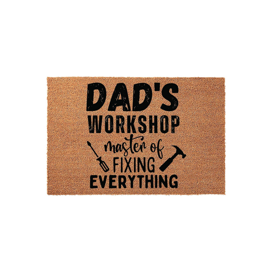 Dad's Workshop Coir Doormat featuring a natural brown fiber texture with bold black text that reads Master of Fixing Everything, accented by small graphic illustrations of a screwdriver and a hammer on a clean white studio