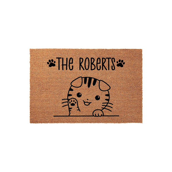 Personalized cat family doormat featuring a cute illustrated tabby kitten waving from behind a line, with space for a custom family name printed in black ink on a natural tan coir fiber background for a welcoming home entrance.